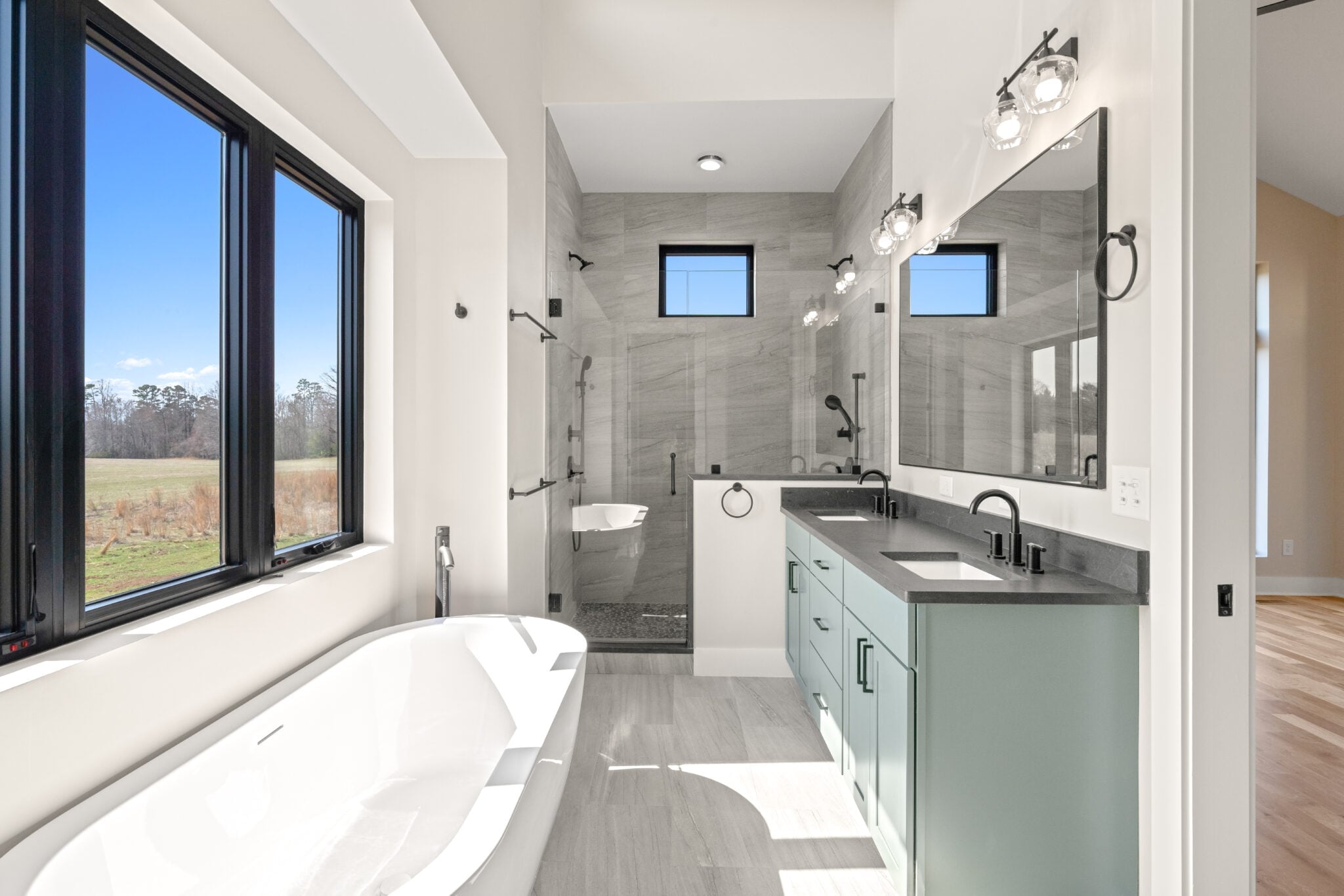 NW 10th St Ankeny 11 1 | CoCreations Construction & Design | CoCreations Construction & Design Modern bathroom with white tub, gray tile, and light vanity | CoCreations Construction & Design | CoCreations Construction & Design